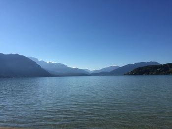 Scenic view of lake and mountains against clear blue sky