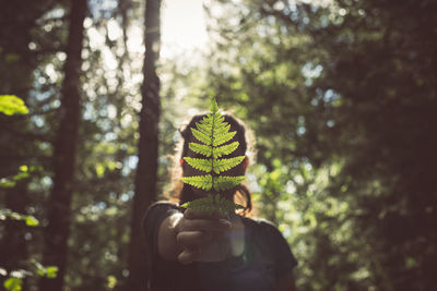 Portrait of man holding plant in forest