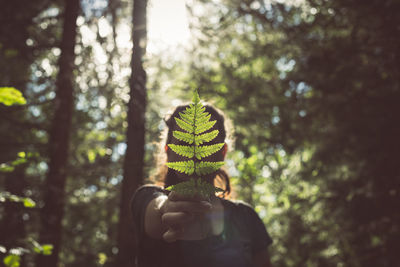 Woman showing leaves in forest