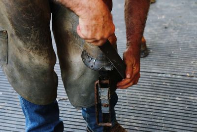 Man putting horse shoe on leg of horse