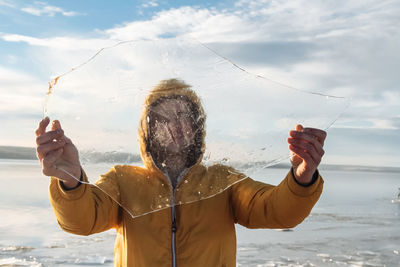 Man holding an ice floe on the seashore in winter