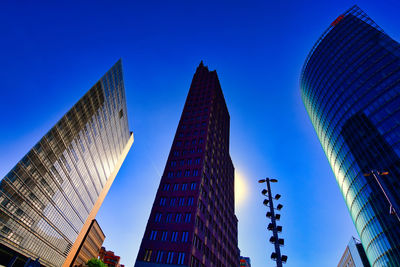 Low angle view of modern buildings against blue sky