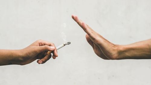 Midsection of man holding cigarette against white background