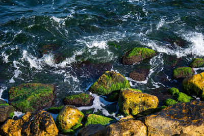 High angle view of rocks in wavy sea