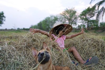 Dog with girl siting on field against sky