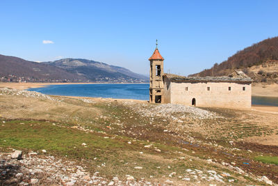 St nicholas church by mavrovo lake against sky