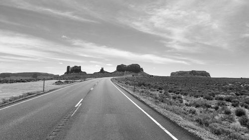 Road leading towards landscape against sky