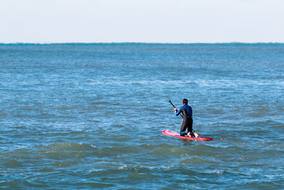 Man surfing in sea against sky