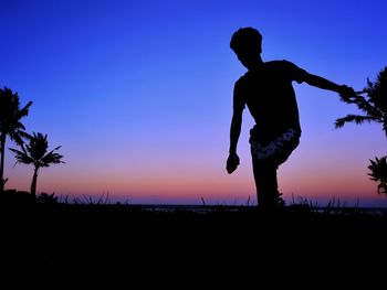 Silhouette man standing on field against sky during sunset