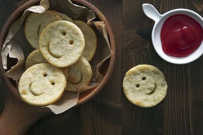 There are some lovely and delicious smiley face potato cakes in the wooden bowl