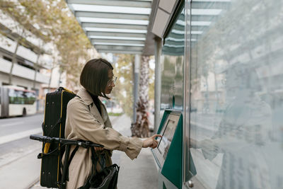 Side view of woman looking through glass