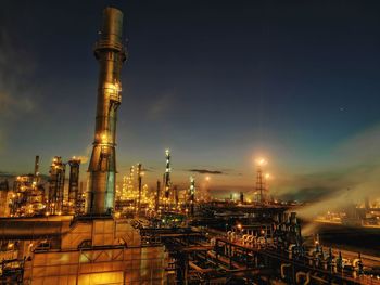 Illuminated factory against sky at night