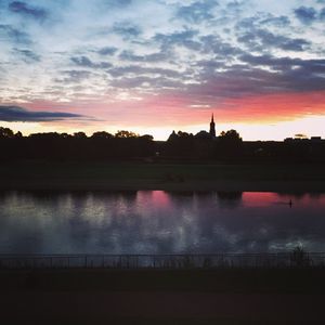 Silhouette of bridge over river against cloudy sky