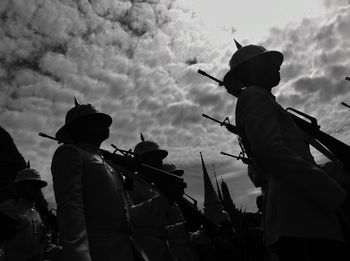 Low angle view of people against cloudy sky