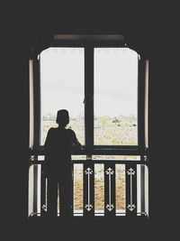 Rear view of silhouette woman standing against window