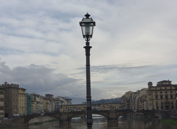 Street light by building against cloudy sky