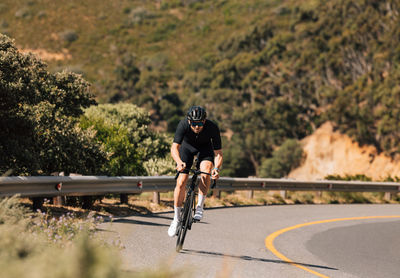 Rear view of man riding bicycle on road