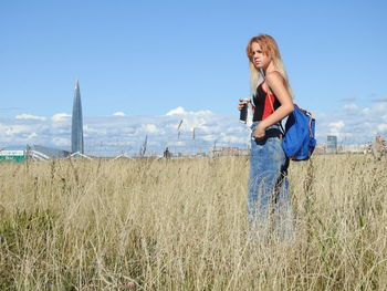 Young girl standing on field against sky