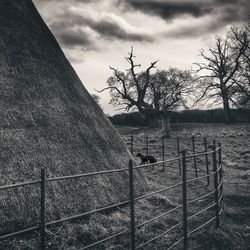 Fence on field against cloudy sky