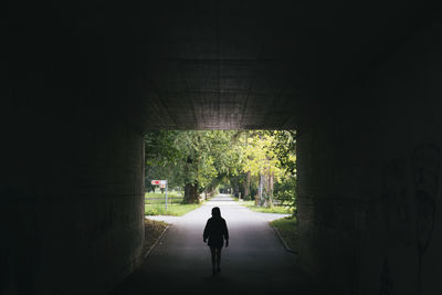 Silhouette of person walking through tunnel