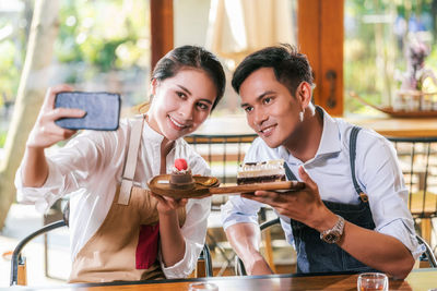 Portrait of a smiling young man using laptop in restaurant