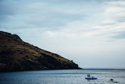 People standing on floating platform in sea against sky