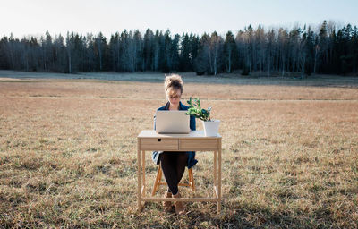 Woman flexible working on a desk and laptop outside in a field