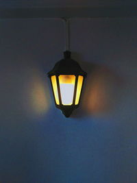 Low angle view of illuminated pendant light mounted on wall