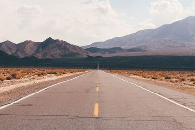 Road leading towards mountains against sky