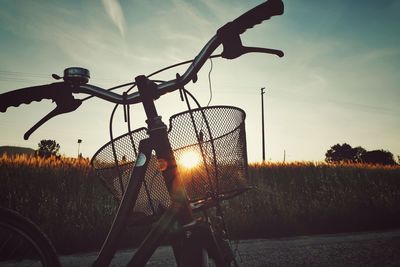 Silhouette bicycle on field against sky during sunset