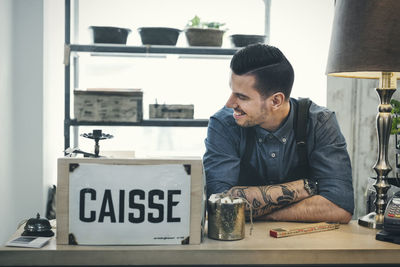 Smiling cashier looking away at cash counter