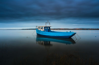 Boat moored in sea against sky at dusk