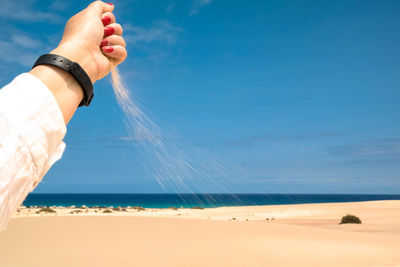 Midsection of person on beach against sky