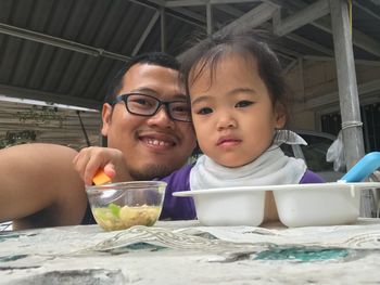 Portrait of smiling man with daughter while eating food