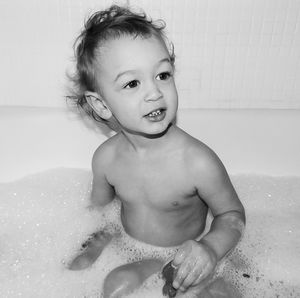 Portrait of cute baby boy sitting in bathtub at home