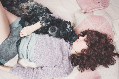 Woman with dog lying on bed at home