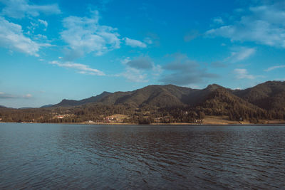 Scenic view of lake and mountains against blue sky