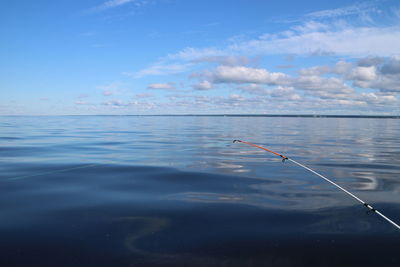 Fishing rod on sea against sky