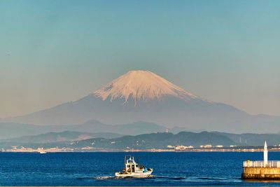 Scenic view of sea and snowcapped mountain against sky during sunrise