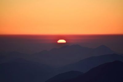 Scenic view of silhouette mountains against romantic sky at sunset