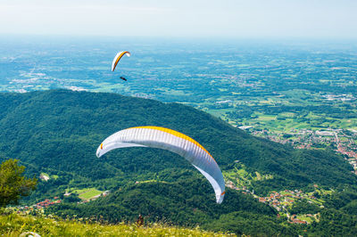 Person paragliding over landscape against sky