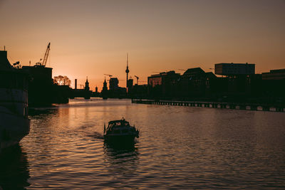 Scenic view of river amidst buildings against sky during sunset