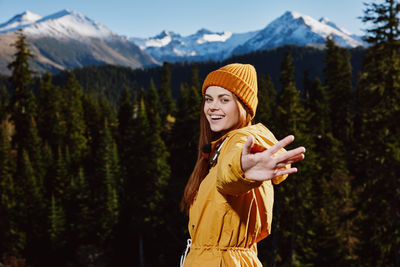 Portrait of smiling young woman standing against mountain