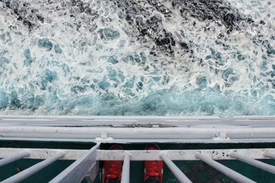 Low section of man standing by railing in boat over sea