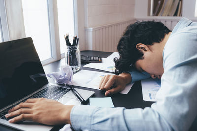 A young businessman who works hard and sleeps at his desk.