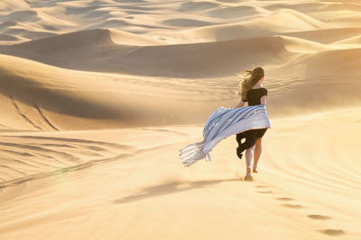 Rear view of woman walking on sand dune