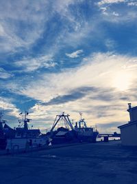 Cranes at harbor against sky in city