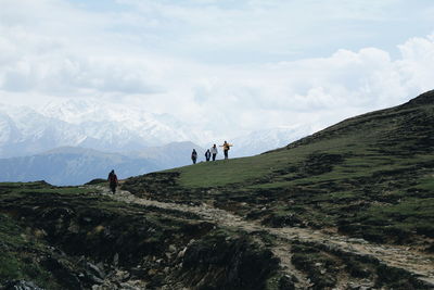 People on mountain against cloudy sky