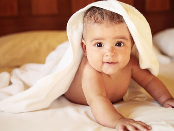 Portrait of cute baby girl lying on bed