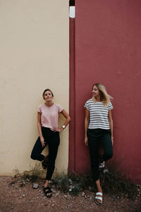 Cheerful friends standing against wall